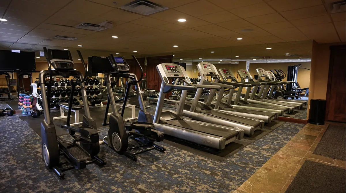 A bright, modern fitness center filled with elliptical machines, treadmills, free weights, and large mirrors. The space is designed for personal and group workouts, offering a motivating environment for guests to maintain their fitness routines.