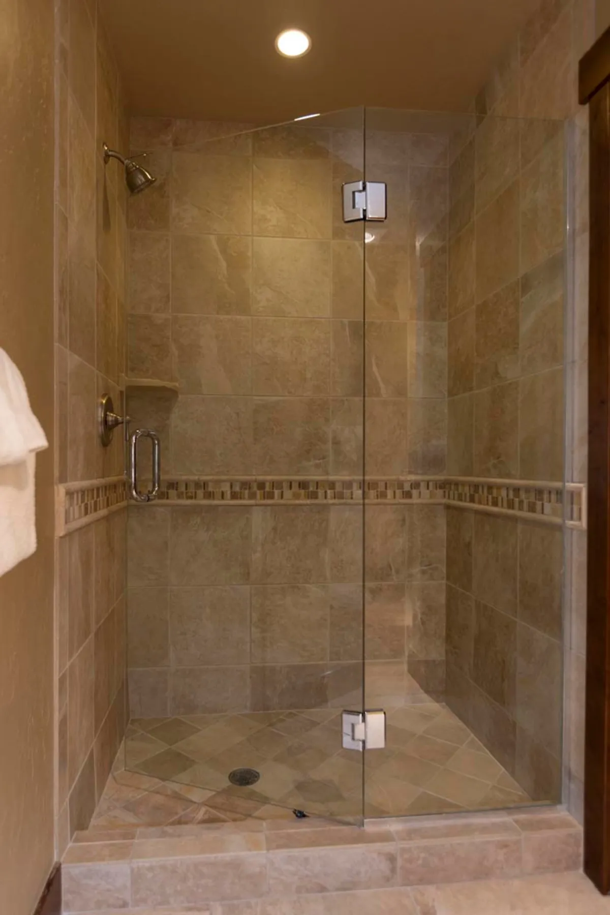 A tranquil glass shower enclosure with textured tiles and a modern shower head, evoking the feeling of a revitalizing, spa-inspired shower experience.