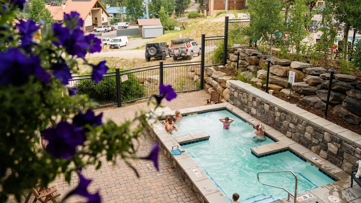 An inviting exterior shot of the swimming pool surrounded by lush greenery and blooming plants. The pool area is spacious, perfect for group gatherings and fun activities under the sun, with ample room for socializing and relaxation.