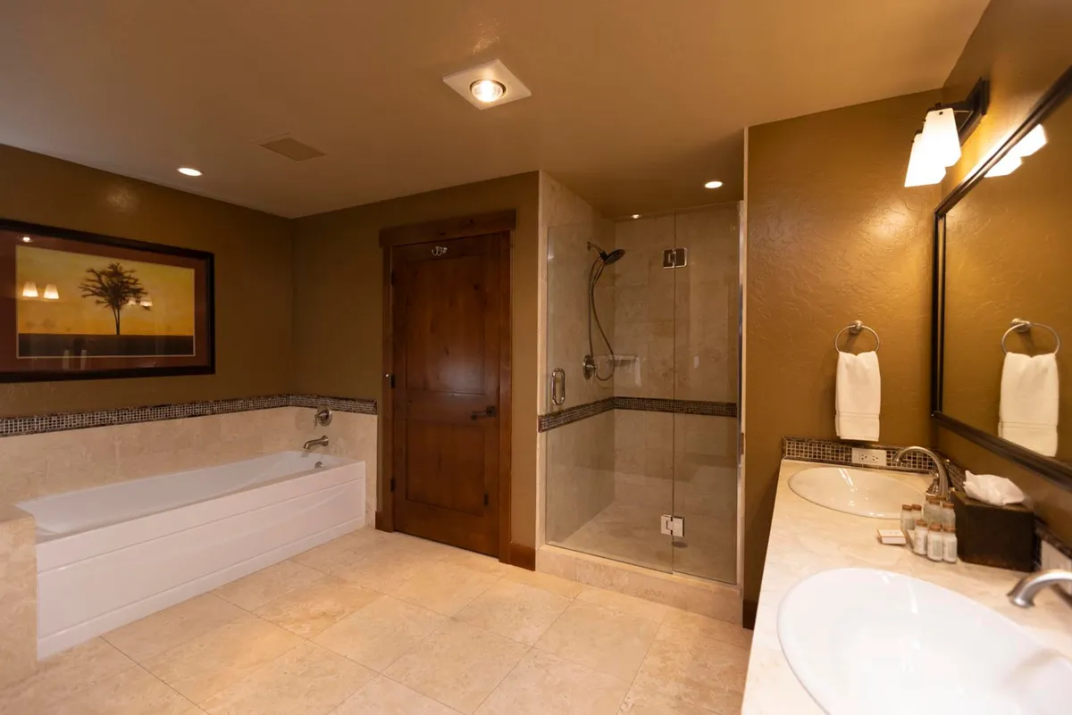 A spa-like bathroom featuring a soaking bathtub, separate glass shower, double sinks, and stylish framed artwork. The space is filled with natural light and designed for relaxation and luxury.