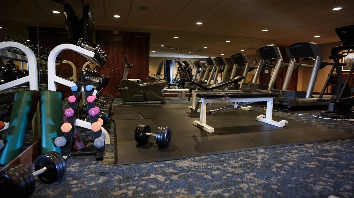 A well-equipped fitness center interior with treadmills, dumbbells, and a weight bench, offering a modern space for group workouts or personal fitness routines. The atmosphere is motivational and energetic, inviting guests to stay active together.